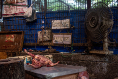 The skinned body of a chicken is seen on a butcher's table, waiting to be cut, in a local meat market. India, 2021. S. Chakrabarti / We Animals