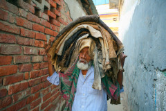An elderly worker carries a dozen cow hides on his head through the narrow streets of Lalbagh, in the centre of Dhaka.